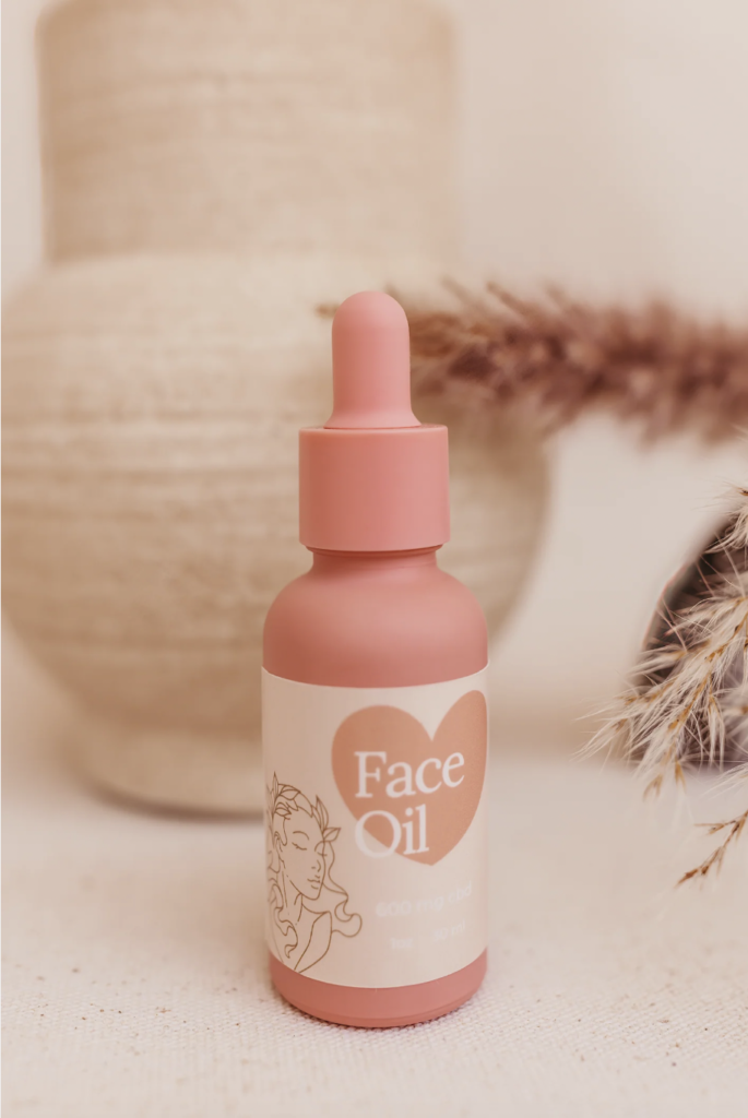 Capri CBD Face Oil in a pink bottle in front of a neutral background